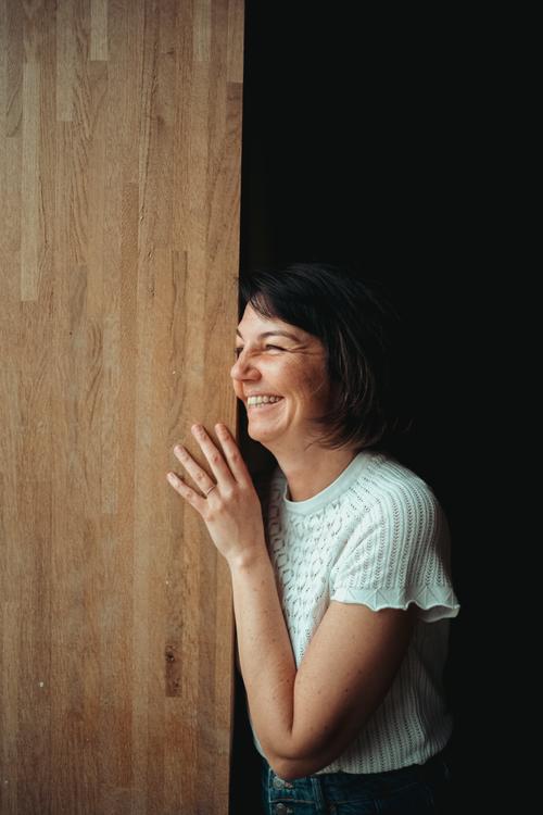 Maria Bitschnau lachend an einer Holzwand