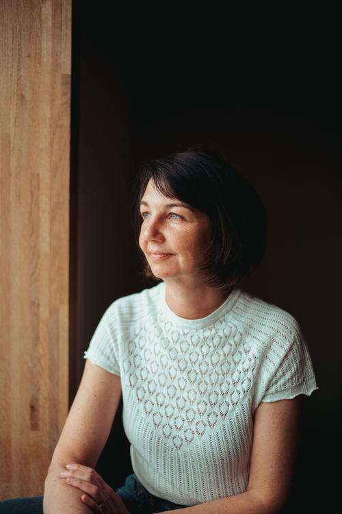 Maria Bitschnau sitzend an einer Holzwand